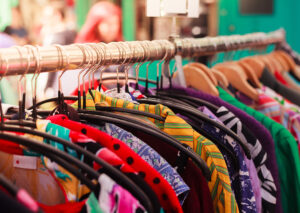 Second-hand clothes of various patterns and styles hanging from a clothing rail.