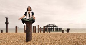 A woman sitting cross-legged on a beam of the wreckage of west pier on Brighton beach